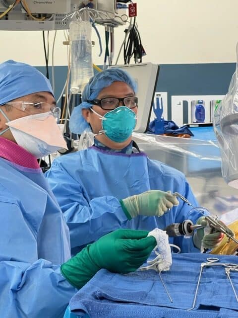 Dr. Lance Mitsunaga using a small camera (aka endoscope) and specialized instruments through a tiny incision to remove the pressure off pinched nerves in a patient’s low back.